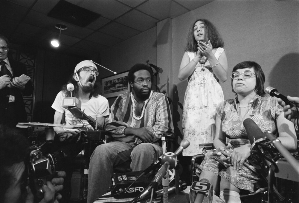 3 people in wheelchairs interviewed whilst a sign-language interpreter stands behind